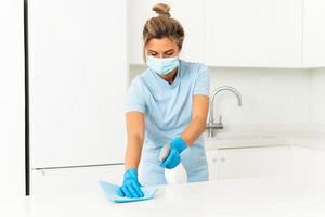 donna lavoratore indossare prevenzione maschera e guanti durante appartamento pulizia foto