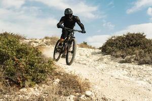 ciclista completamente attrezzata con protettivo Ingranaggio durante discesa cavalcata su il suo bicicletta foto