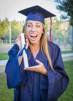 espressive giovane donna Tenere diploma nel berretto e toga foto