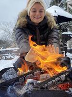 giovane donna riscaldamento su di il fuoco fossa durante freddo inverno giorno foto