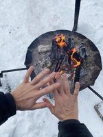 donna riscaldamento su sua mani di il fuoco fossa foto