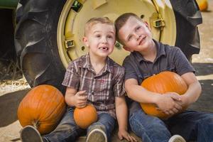 Due ragazzi avendo divertimento a il zucca toppa su un' autunno giorno. foto