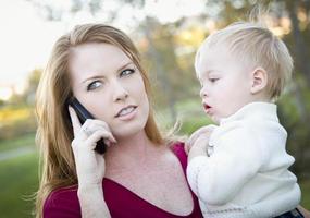 attraente donna utilizzando cellula Telefono con bambino foto