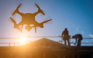 silhouette di senza equipaggio aereo sistema quadcopter fuco nel il aria al di sopra di edificio sotto costruzione. foto