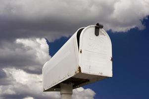 Esposto alle intemperie vecchio cassetta postale contro blu cielo e nuvole foto