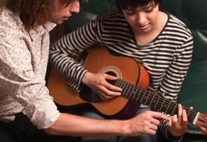 giovane musicista insegna femmina alunno per giocare il chitarra foto