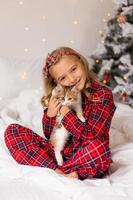 un' contento poco ragazza ricevuto un' carino gattino come un' regalo per il nuovo anno. Natale mattina. alto qualità foto