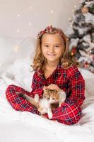 un' contento poco ragazza ricevuto un' carino gattino come un' regalo per il nuovo anno. Natale mattina. alto qualità foto