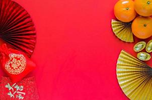 Cinese nuovo anno concetto con rosso Busta pacchetti o ang bao parola significare auspicio, rosso Borsa parola significare ricchezza, lingotti e arance su rosso sfondo con d'oro e rosso orientale fan. foto