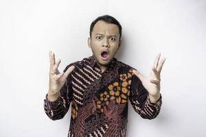 scioccato indonesiano uomo indossare batik camicia e guardare su, isolato di bianca sfondo foto