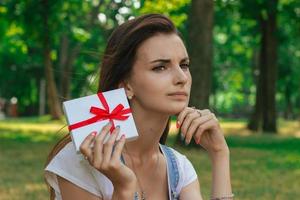 ritratto di un' bellissimo ragazza con riflessivo poco regalo nel mano foto