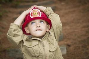 adorabile bambino ragazzo con vigile del fuoco cappello giocando al di fuori foto