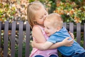 giovane sorella e fratello avendo divertimento su il panchina a il parco foto