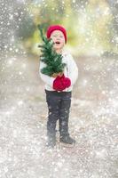 bambino ragazza nel guanti Tenere piccolo Natale albero con neve effetto foto