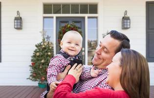 contento giovane famiglia su davanti veranda di Casa con Natale decorazioni foto