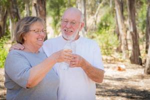 contento salutare anziano coppia con acqua bottiglie foto