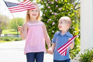 giovane sorella e fratello agitando americano bandiere a il parco foto