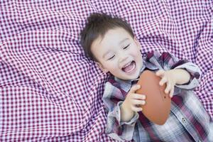 giovane ragazzo di razza mista, giocando con il calcio sulla coperta da picnic foto