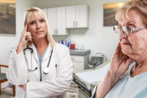 empatico medico in piedi dietro a turbato anziano adulto donna nel ufficio foto