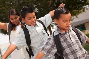 carino fratelli e sorella avendo divertimento a piedi per scuola foto