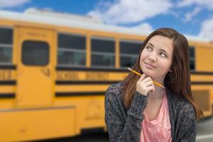 giovane femmina alunno vicino scuola autobus foto