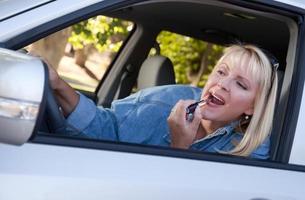 donna mettendo su rossetto mentre guida foto