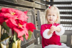 adorabile poco ragazza seduta su panchina con sua caramella canna foto