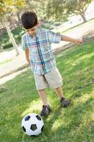 giovane ragazzo sveglio che gioca con il pallone da calcio all'aperto nel parco. foto