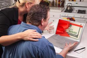 coppia nel cucina utilizzando il computer portatile - i soldi foto