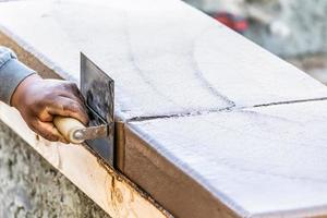 costruzione lavoratore utilizzando inossidabile acciaio bordatore su bagnato cemento formatura cimasa in giro nuovo piscina foto