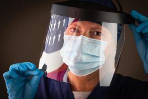 americano bandiera riflettendo su femmina medico lavoratore indossare protettivo viso maschera e scudo foto