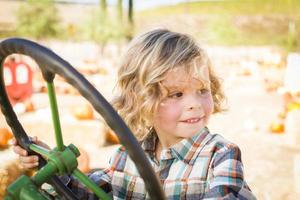 poco ragazzo avendo divertimento nel un' trattore nel un' rustico ranch ambientazione a il zucca toppa. foto