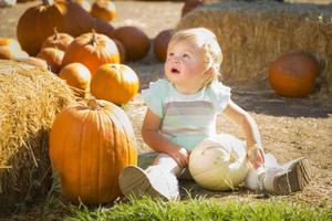 adorabile bambino ragazza avendo divertimento nel un' rustico ranch ambientazione a il zucca toppa. foto