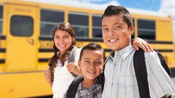 giovane ispanico ragazzi e ragazza a piedi vicino scuola autobus foto