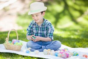 misto gara Cinese e caucasico ragazzo al di fuori indossare coniglio orecchie giocando con Pasqua uova foto