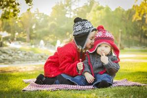 poco ragazza sussurra un' segreto per bambino fratello all'aperto foto