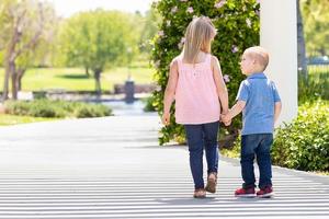 giovane sorella e fratello Tenere mani e a piedi a il parco foto