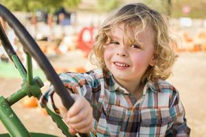 adorabile giovane ragazzo giocando su un vecchio trattore al di fuori foto