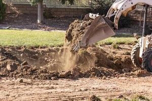 piccolo bulldozer scavando nel cortile per piscina installazione foto