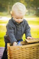 bionda bambino ragazzo apertura picnic cestino all'aperto a il parco foto