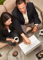 uomo e donna utilizzando il computer portatile con caffè foto