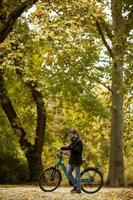 bel giovane con bicicletta elettrica nel parco autunnale foto