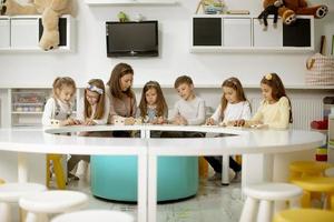 gruppo di carino poco bambini giocando con prescolastico educativo giocattoli con asilo insegnante foto