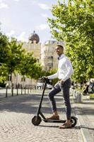 giovane afroamericano utilizzando scooter elettrico su una strada foto