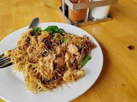 agitare fritte riso vermicelli spaghetto con nero soia salsa su di legno tavolo. popolare tailandese cibo foto