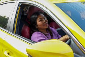 contento sorridente asiatico donna guidare un' luminosa giallo auto partire su vacanza. morbido e selettivo messa a fuoco. foto