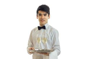 affascinante Cameriere nel un' bianca camicia Tenere un' vassoio con bicchieri di alcool foto