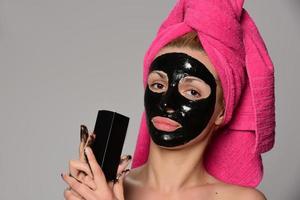 bellissimo femmina modello con nero facciale cosmetico maschera. isolato su grigio sfondo foto