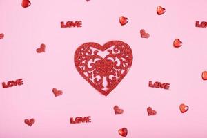 luccichio rosso cuore e piccolo cuori su rosa sfondo. san valentino giorno sfondo foto