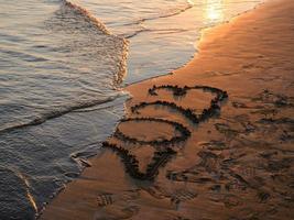 nuovo anno concetto foto. numeri 2023 manoscritto nel il sabbia superficie. morbido mare onda e spiaggia su sfondo. foto